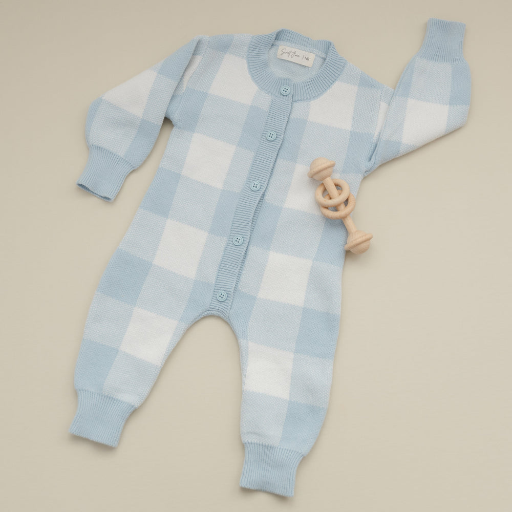 Blue and white checkered baby onesie on a beige background
