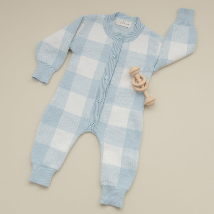 Blue and white checkered baby onesie on a beige background