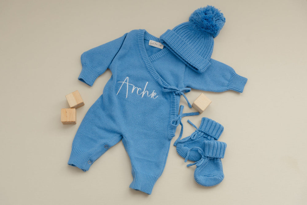 Personalized Blue baby outfit with cardigan, hat, and booties on a beige background- Sweet June